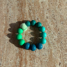 „Aqua Breeze Armband in Blau und Türkis auf einem Tisch liegend, Sym Aesthetics.“