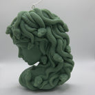 Handgemachte Medusas Whispering Flames Kerze aus Sojawachs in Dunkelgrün mit detaillierten Schlangen auf dem Kopf – einzigartige Medusa-Kerze im Mythologie-Design für Fantasy-Liebhaber.
